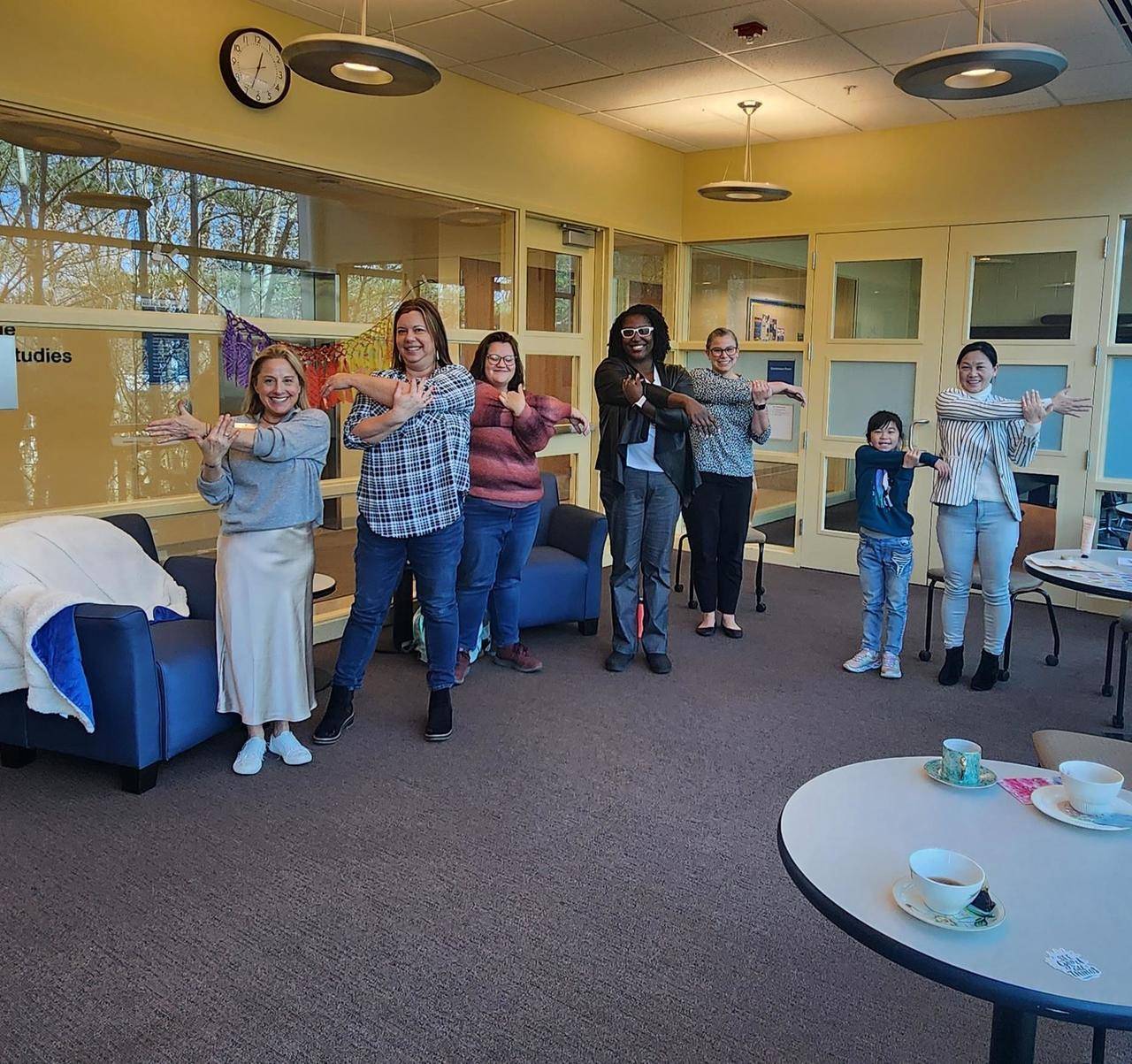 a group of people stretching their arms across their bodies while smiling for the camera